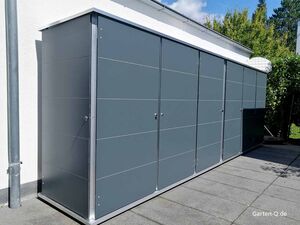 . Graues Garten-Lagerhaus mit mehreren Türen an einer weißen Wand, Pavillon und Pflanzen im Hintergrund.