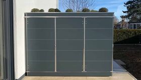 Modernes Gartenhaus an einer Wand mit Pflanzen auf dem Dach.