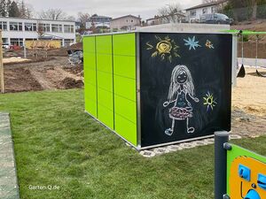 Grünes Modul mit Kreidemalzeichnung eines Mädchens, Sonne und Sternen, Hintergrund mit Rasen und Gebäuden.