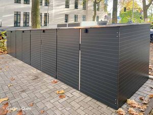 Große, moderne Außenschränke aus Metall auf einem gepflasterten Hof mit Herbstlaub.